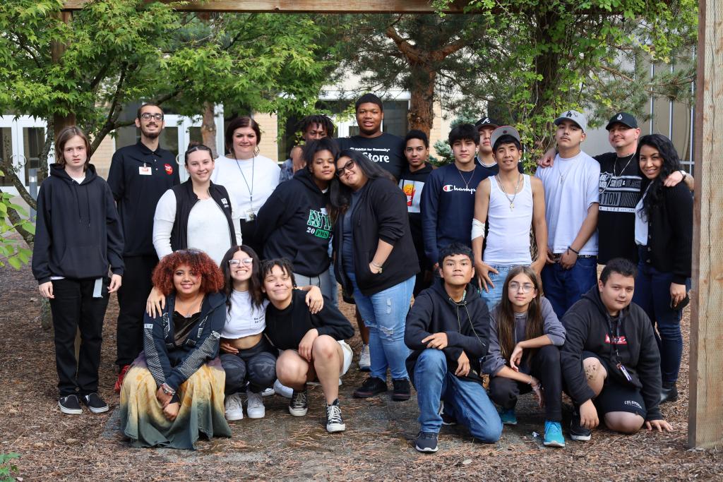 Group of youth and mentors stand together in an outdoor courtyard.